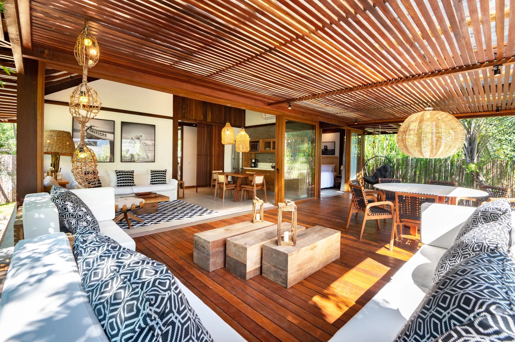 Living e varanda integrados, com madeira natural, luminárias artesanais e portas abertas para o jardim